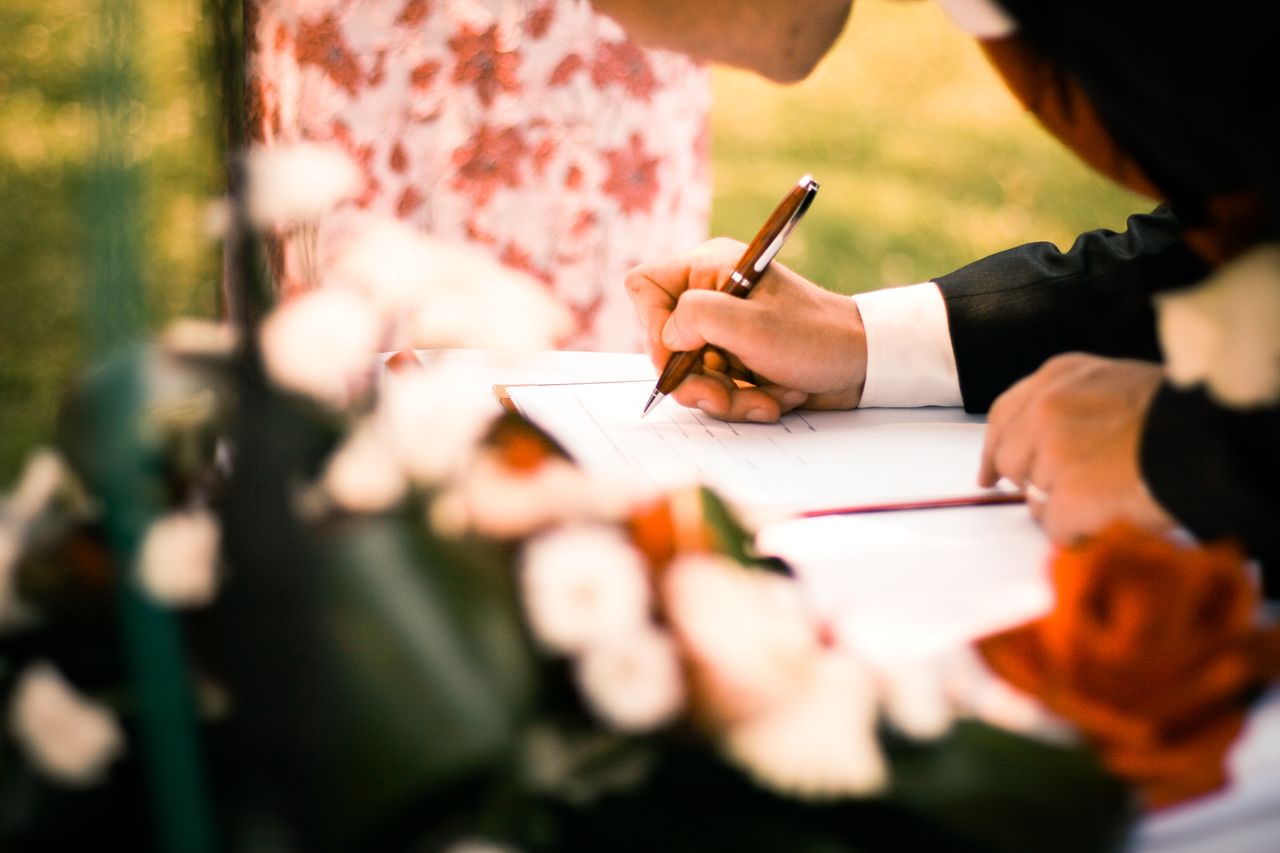 Crafting Captivating Headlines: Your awesome post title goes here A close-up of hands signing a marriage contract during an outdoor wedding ceremony